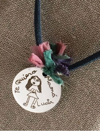 collar con elástico seda medalla 25 mm. grabada con dibujo de niño medalla con bolitas plata y pompón de seda de colores